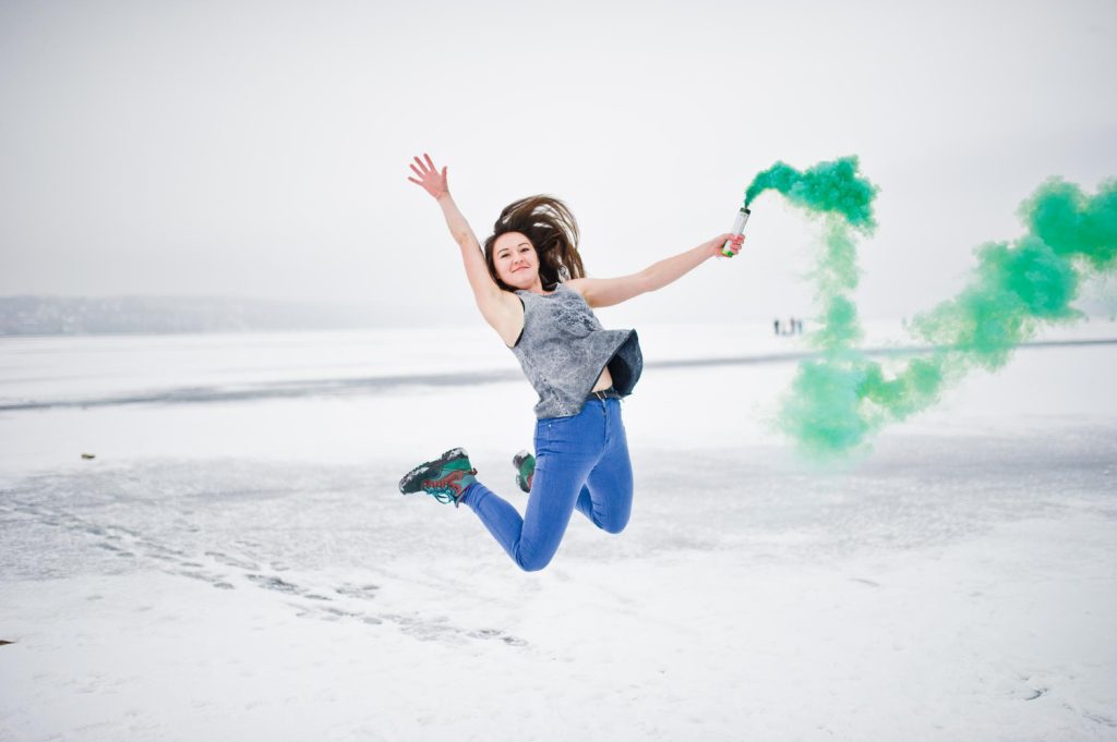 fille qui saute avec un fumigene vert